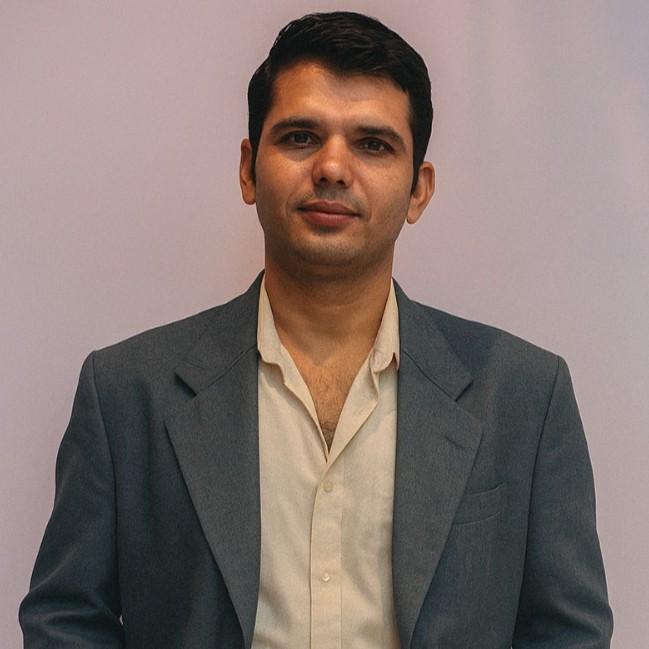 Portrait of Mr. Mahesh Bairagi wearing a red t-shirt standing in front of a lush green garden with soft evening lights